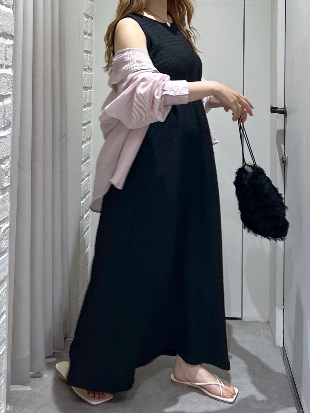 ブラック系のワンピース、ブラック系のハンドバッグ、ホワイト系のサンダルを着用したレディースの夏コーディネートの4枚目の写真