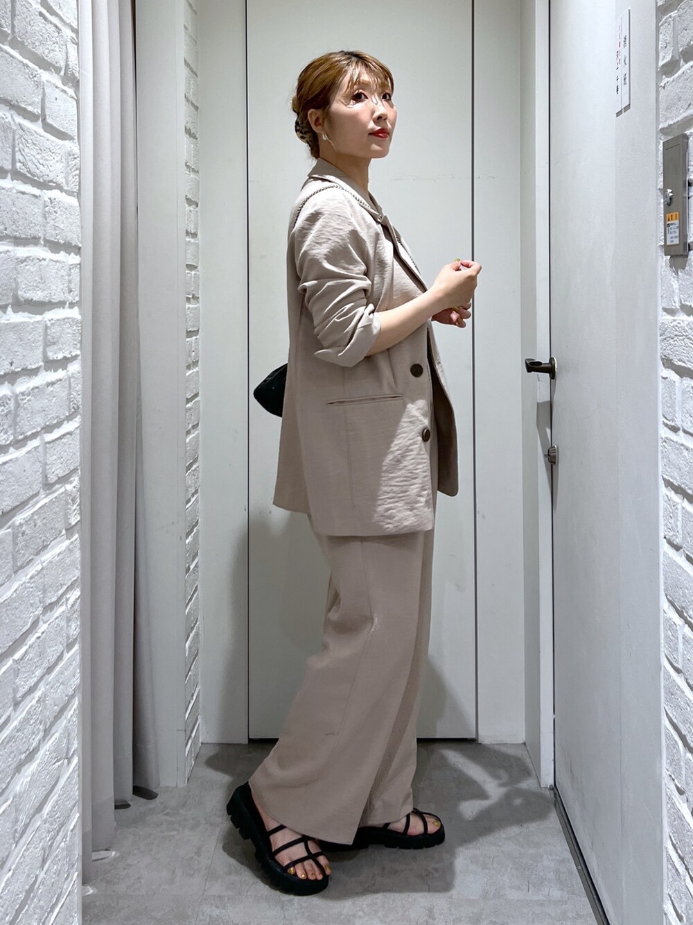 ベージュ系のテーラードジャケット、ベージュ系のスラックス、ブラック系のタンクトップを着用したレディースの夏コーディネートの3枚目の写真