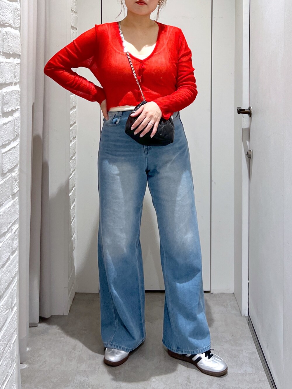 ブルー系のデニムパンツ、レッド系のカーディガン/ボレロ、ブラック系のショルダーバッグを着用したレディースの夏コーディネートの4枚目の写真