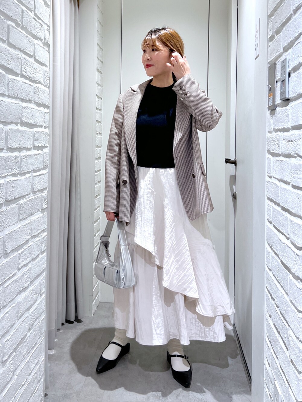ブラウン系のテーラードジャケット、ホワイト系のスカート、ブラック系のパンプスを着用したレディースの春コーディネートの2枚目の写真