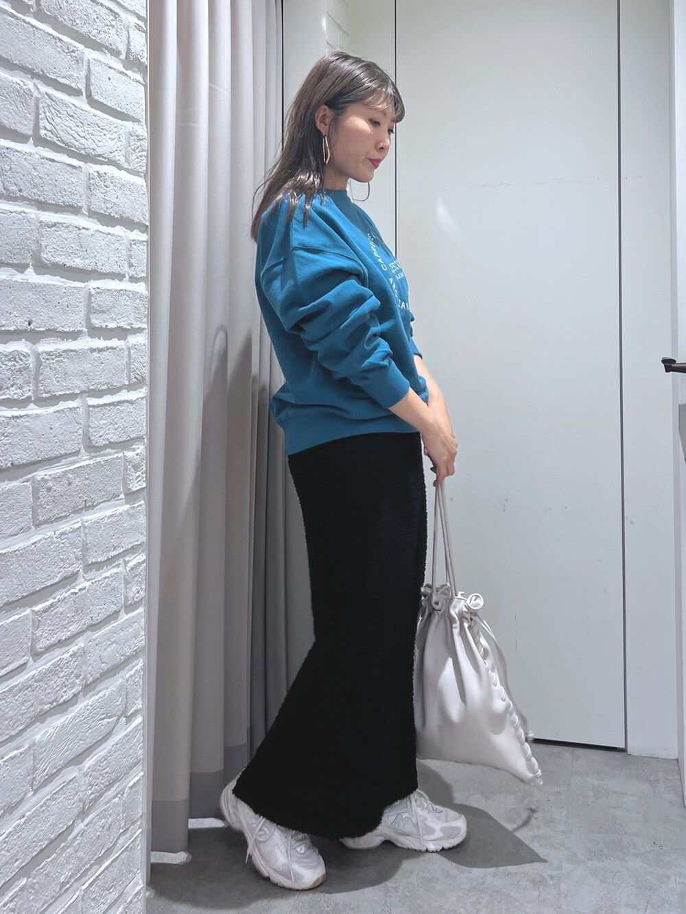 ブラック系のスカート、グリーン系のスウェット、ホワイト系のハンドバッグを着用したレディースの秋コーディネートの4枚目の写真