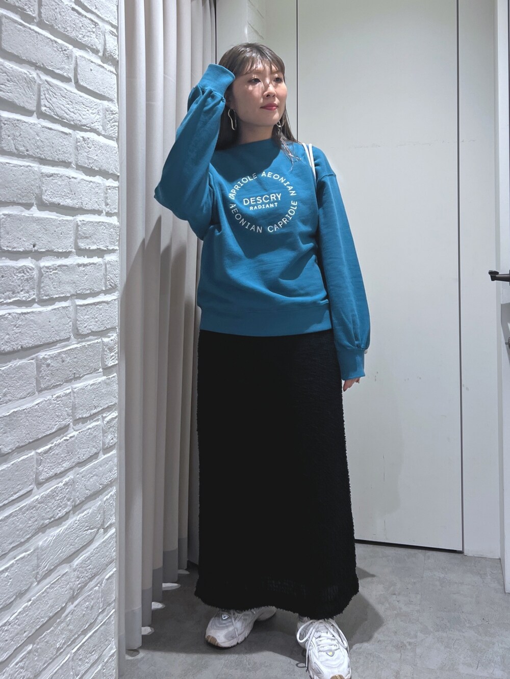 ブラック系のスカート、グリーン系のスウェット、ホワイト系のハンドバッグを着用したレディースの秋コーディネートの2枚目の写真