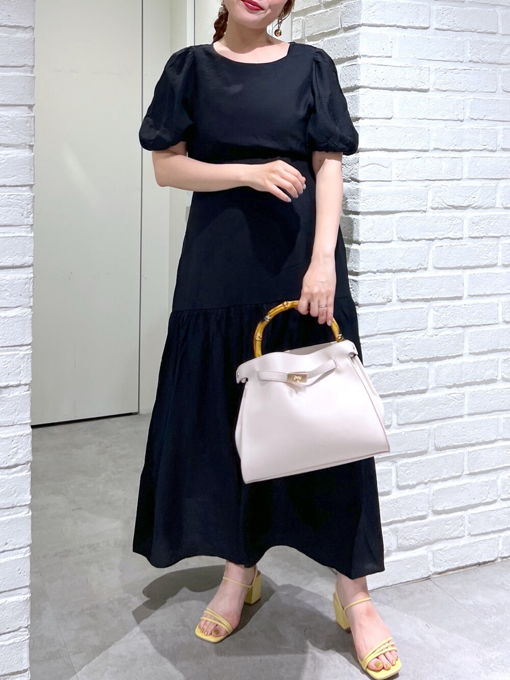 ホワイト系のショルダーバッグ、ブラック系のワンピース、イエロー系のサンダルを着用したレディースの夏コーディネートの6枚目の写真