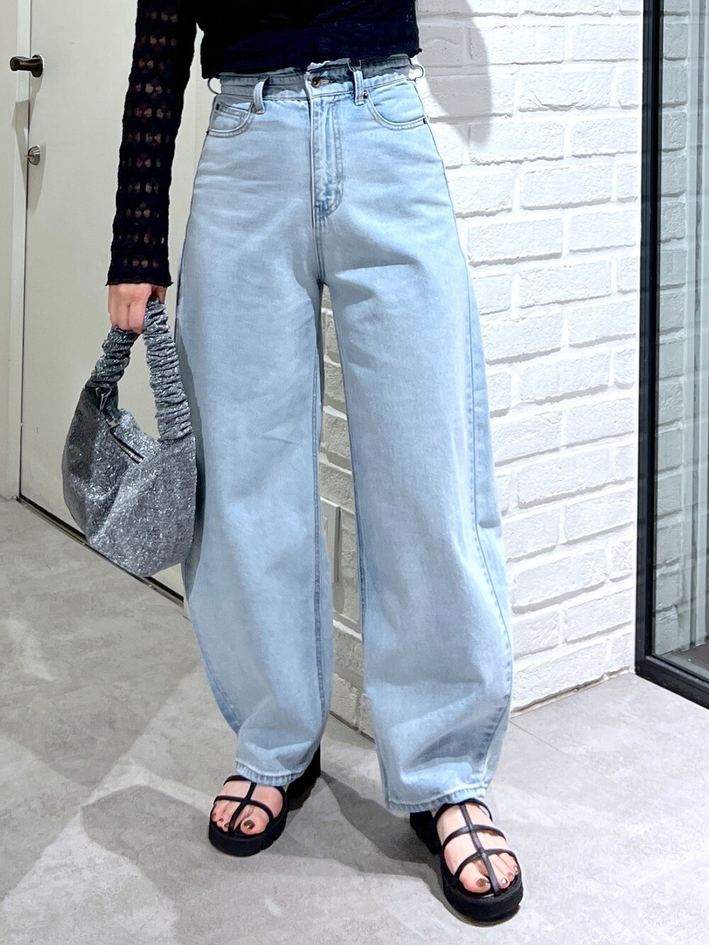 ブルー系のデニムパンツ、ブラック系のサンダル、シルバー系のハンドバッグを着用したレディースの夏コーディネートの6枚目の写真