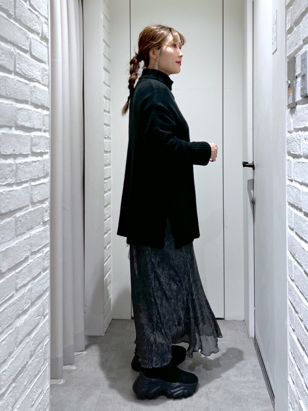 ブラック系のニット/セーター、ブラック系のスカート、ブラック系のブーツを着用したレディースの冬コーディネートの6枚目の写真