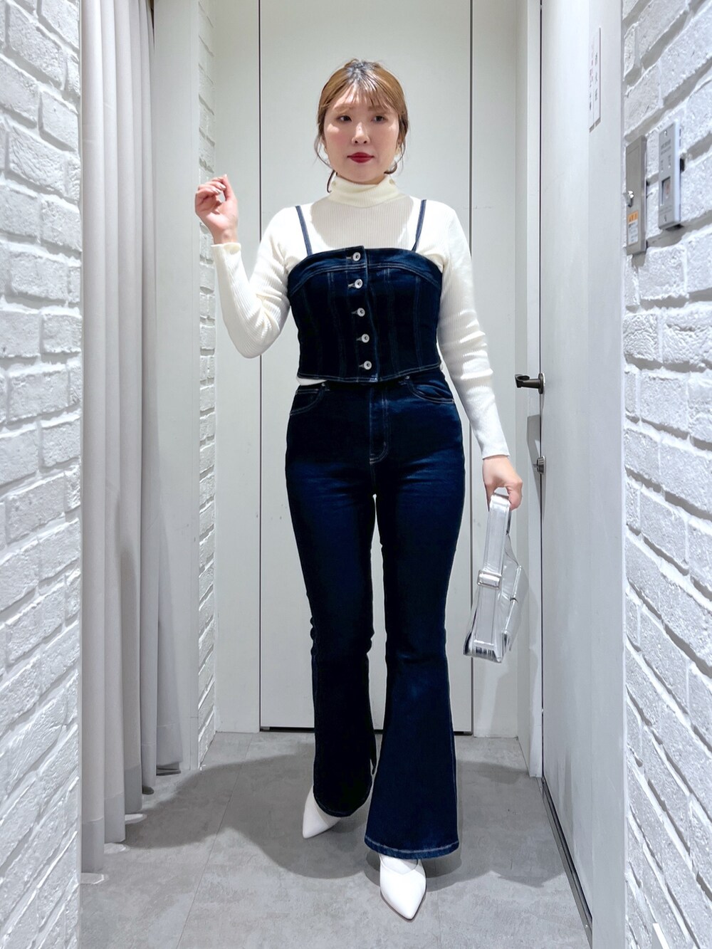 ブルー系のデニムパンツ、ホワイト系のパンプス、ブルー系のベストを着用したレディースの冬コーディネートの5枚目の写真