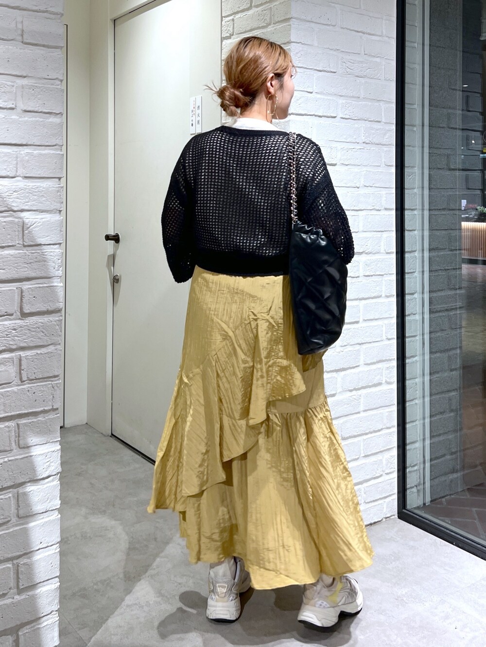 イエロー系のスカート、ブラック系のカーディガン/ボレロ、ホワイト系のTシャツ/カットソーを着用したレディースの夏コーディネートの7枚目の写真