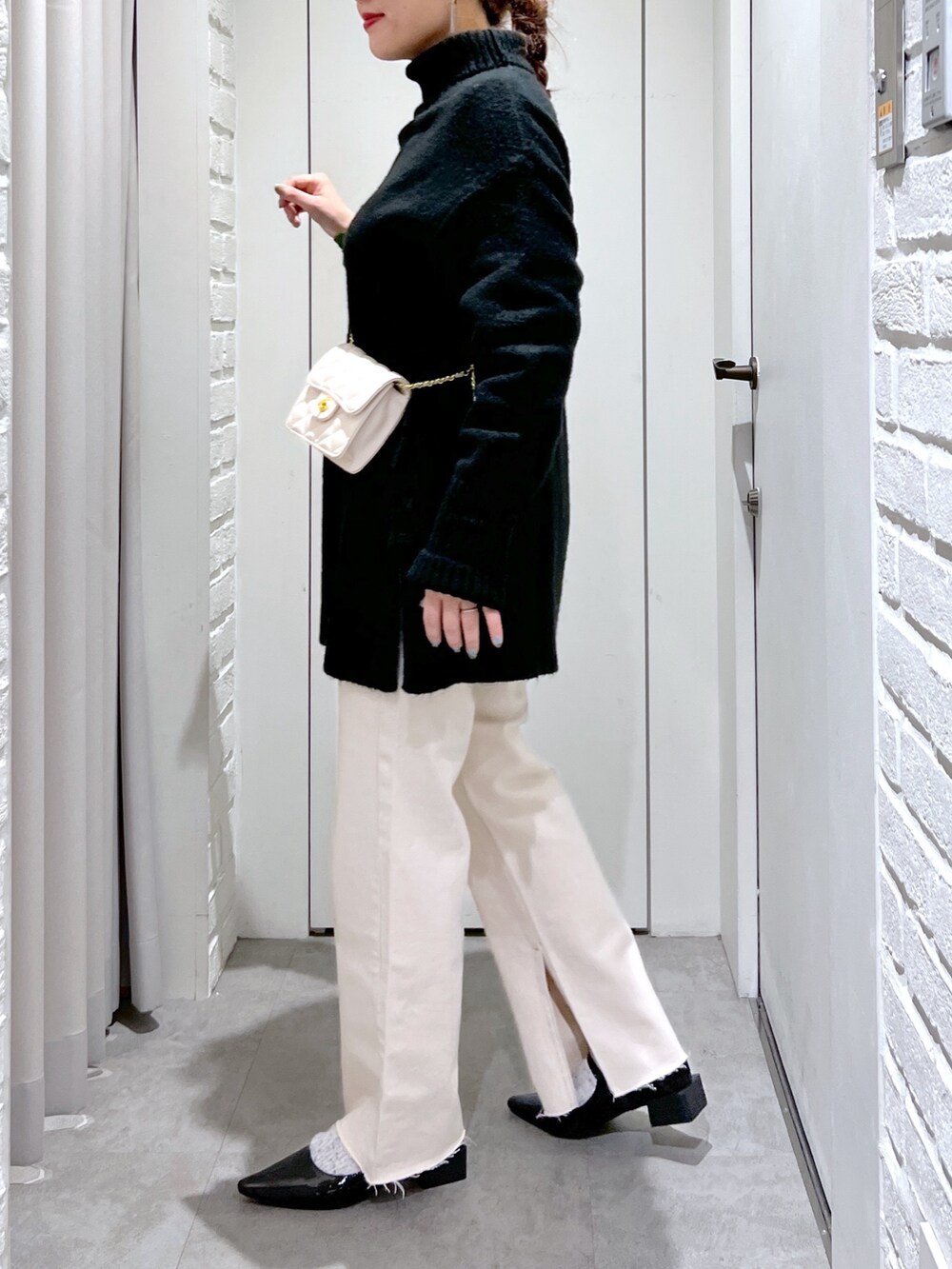 ブラック系のニット/セーター、ホワイト系のデニムパンツ、ブラック系のバレエシューズを着用したレディースの冬コーディネートの5枚目の写真