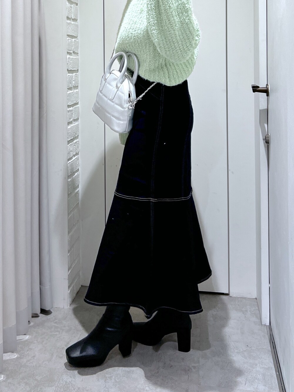 ブルー系のスカート、グリーン系のニット/セーター、シルバー系のショルダーバッグを着用したレディースの冬コーディネートの6枚目の写真