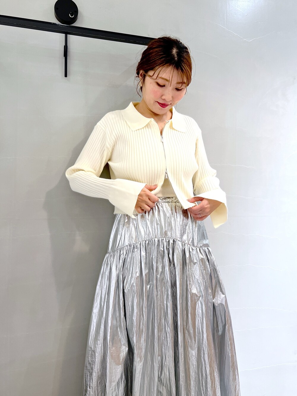 シルバー系のスカート、ホワイト系のニット/セーター、ブラック系のトートバッグを着用したレディースの冬コーディネートの5枚目の写真