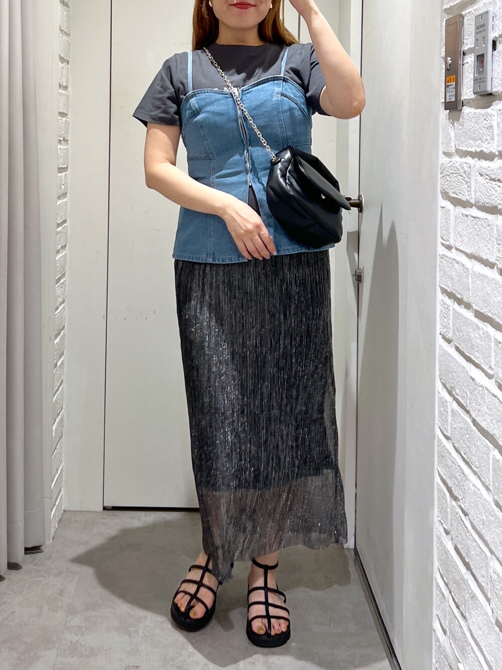 ブラック系のスカート、ブルー系のベスト、ブラック系のショルダーバッグを着用したレディースの夏コーディネートの5枚目の写真