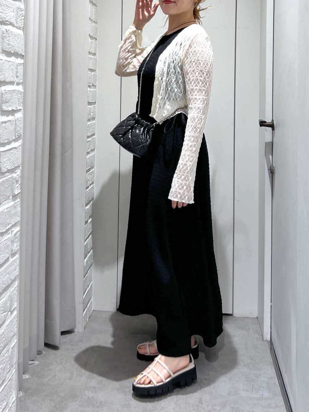 ブラック系のワンピース、ホワイト系のカーディガン/ボレロ、ホワイト系のサンダルを着用したレディースの夏コーディネートの6枚目の写真