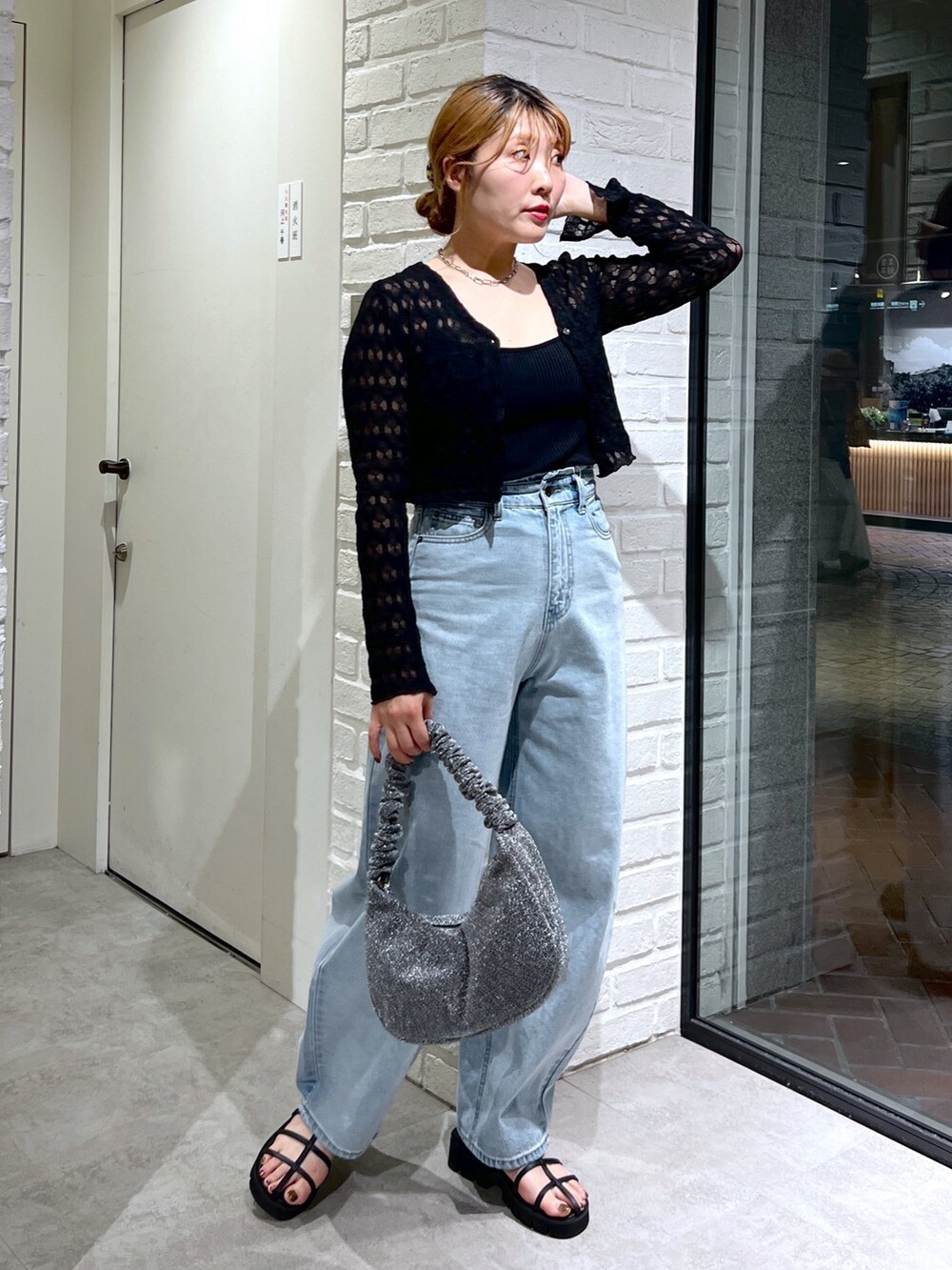 ブルー系のデニムパンツ、ブラック系のサンダル、シルバー系のハンドバッグを着用したレディースの夏コーディネートの2枚目の写真