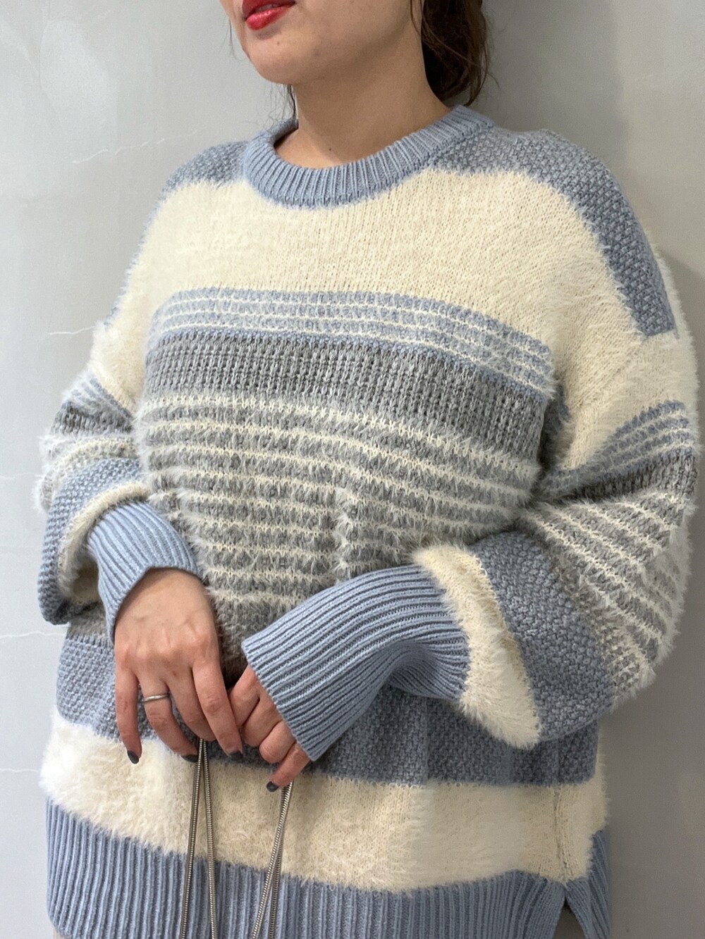 ブルー系のニット/セーター、ホワイト系のスカート、シルバー系のショルダーバッグを着用したレディースの冬コーディネートの8枚目の写真