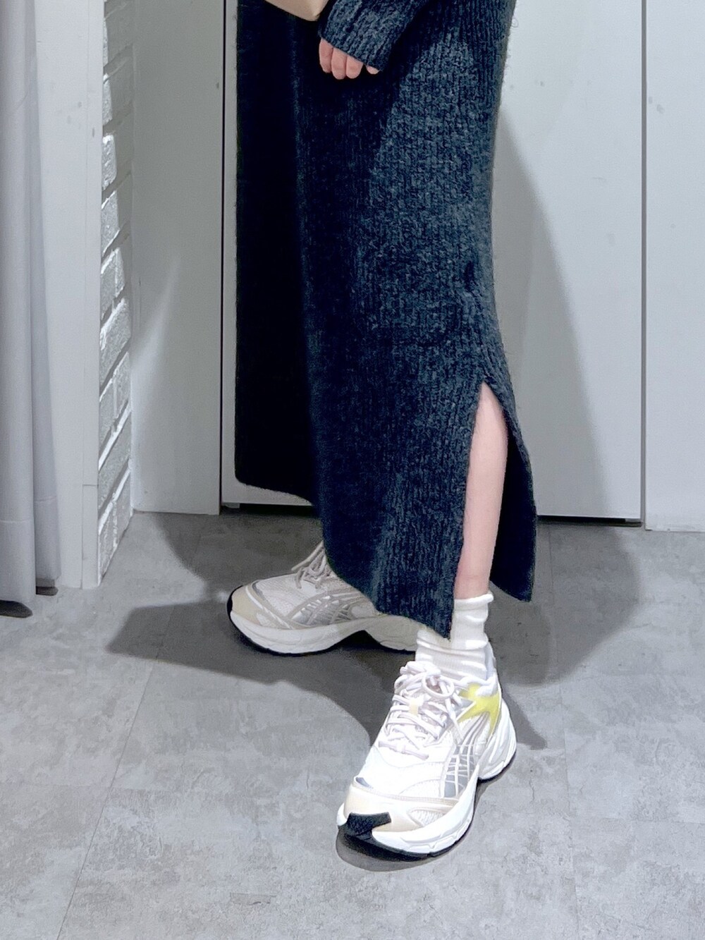 ブラック系のワンピース、ホワイト系のスニーカー、ベージュ系のショルダーバッグを着用したレディースの冬コーディネートの4枚目の写真