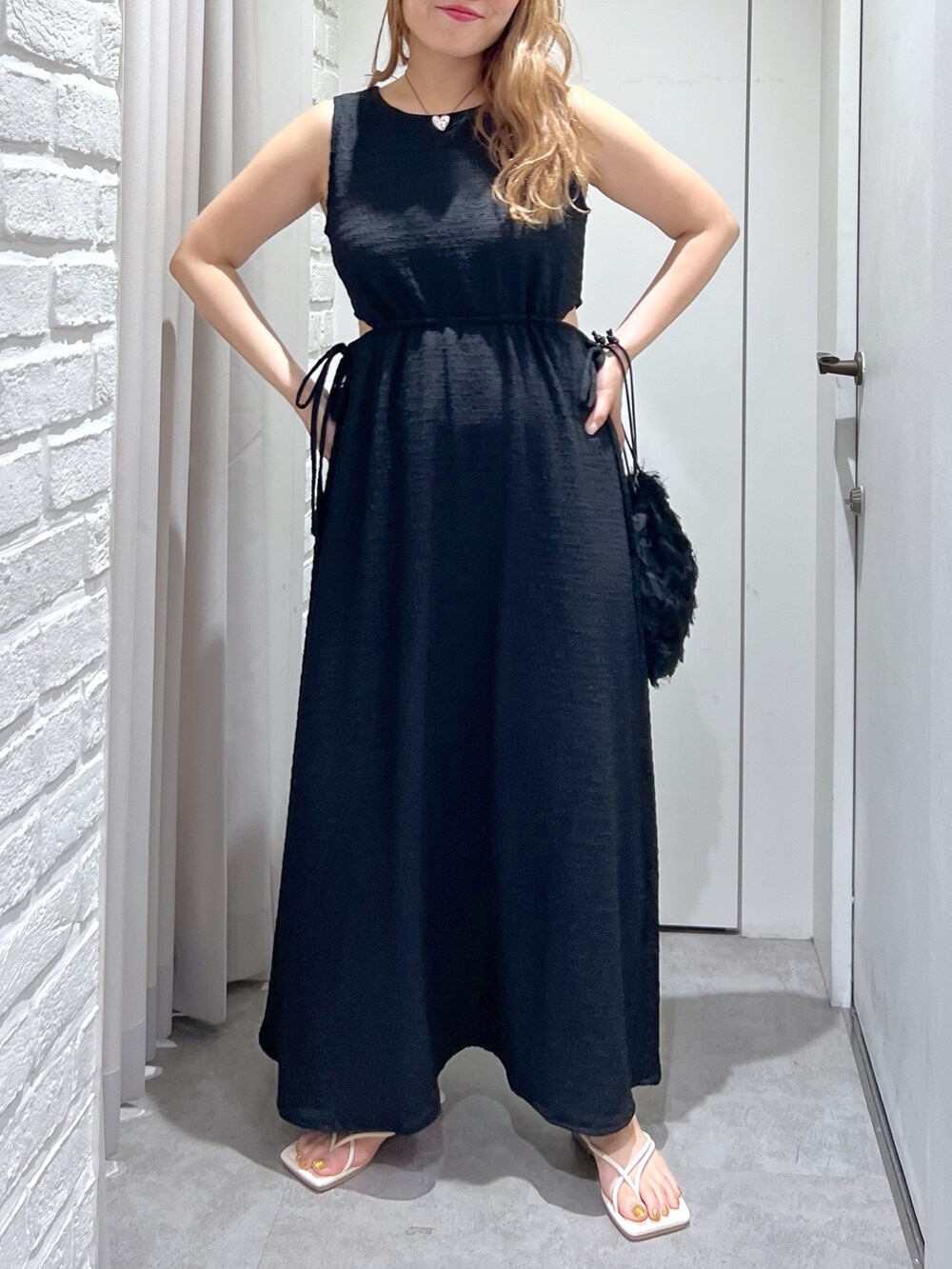 ブラック系のワンピース、ブラック系のハンドバッグ、ホワイト系のサンダルを着用したレディースの夏コーディネートの6枚目の写真