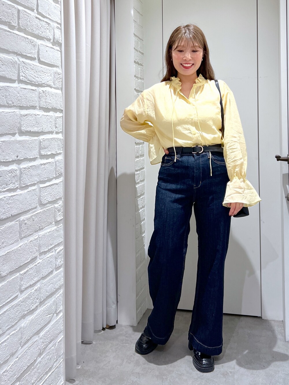 ブルー系のデニムパンツ、イエロー系のシャツ/ブラウス、ブラック系のショルダーバッグを着用したレディースの秋コーディネートの4枚目の写真