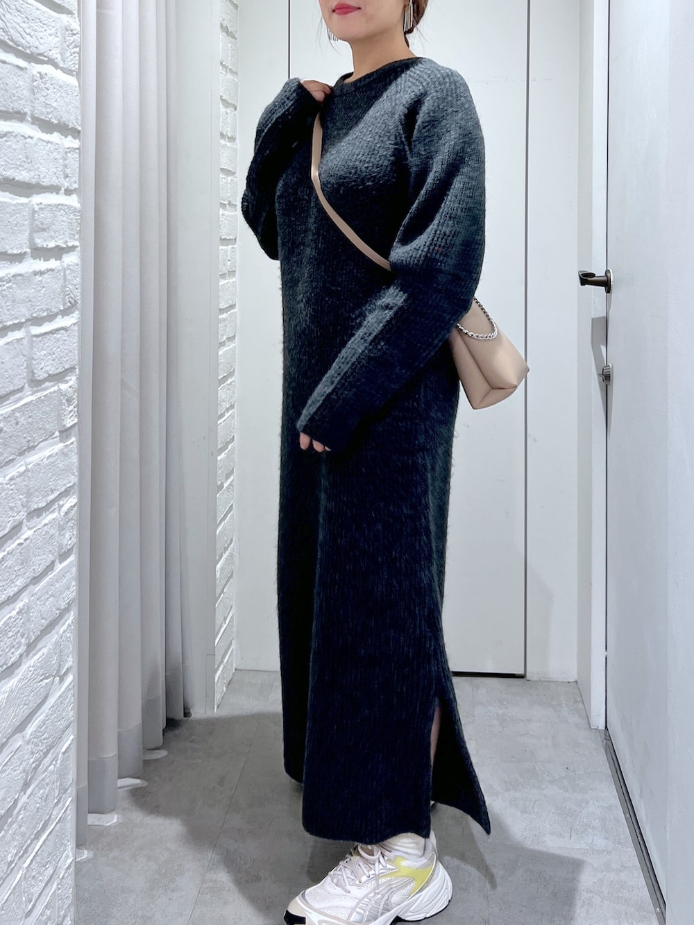 ブラック系のワンピース、ホワイト系のスニーカー、ベージュ系のショルダーバッグを着用したレディースの冬コーディネートの3枚目の写真