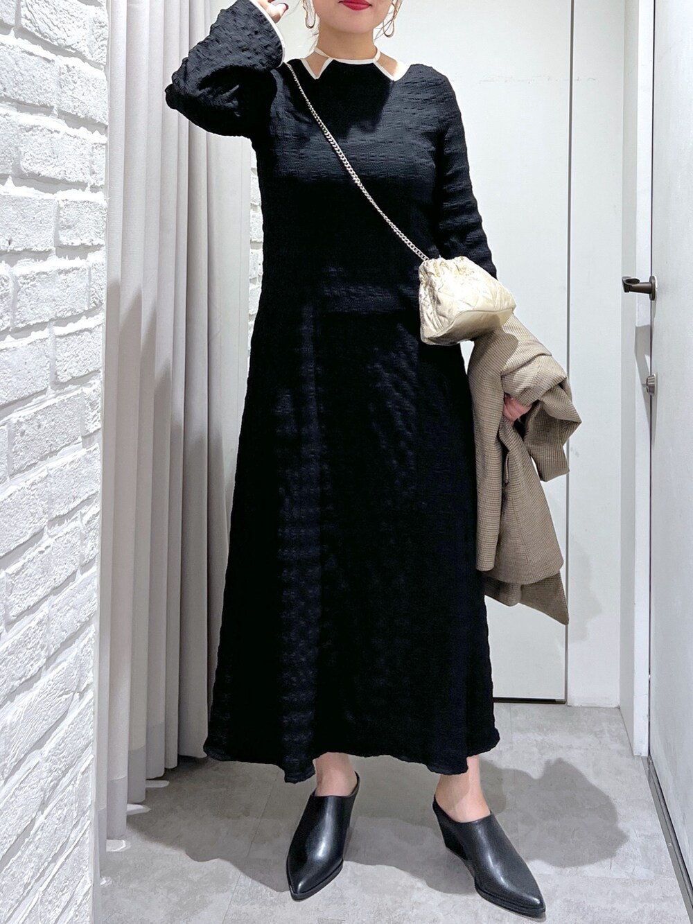 ブラック系のワンピース、ブラック系のパンプス、ゴールド系のショルダーバッグを着用したレディースの春コーディネートの7枚目の写真