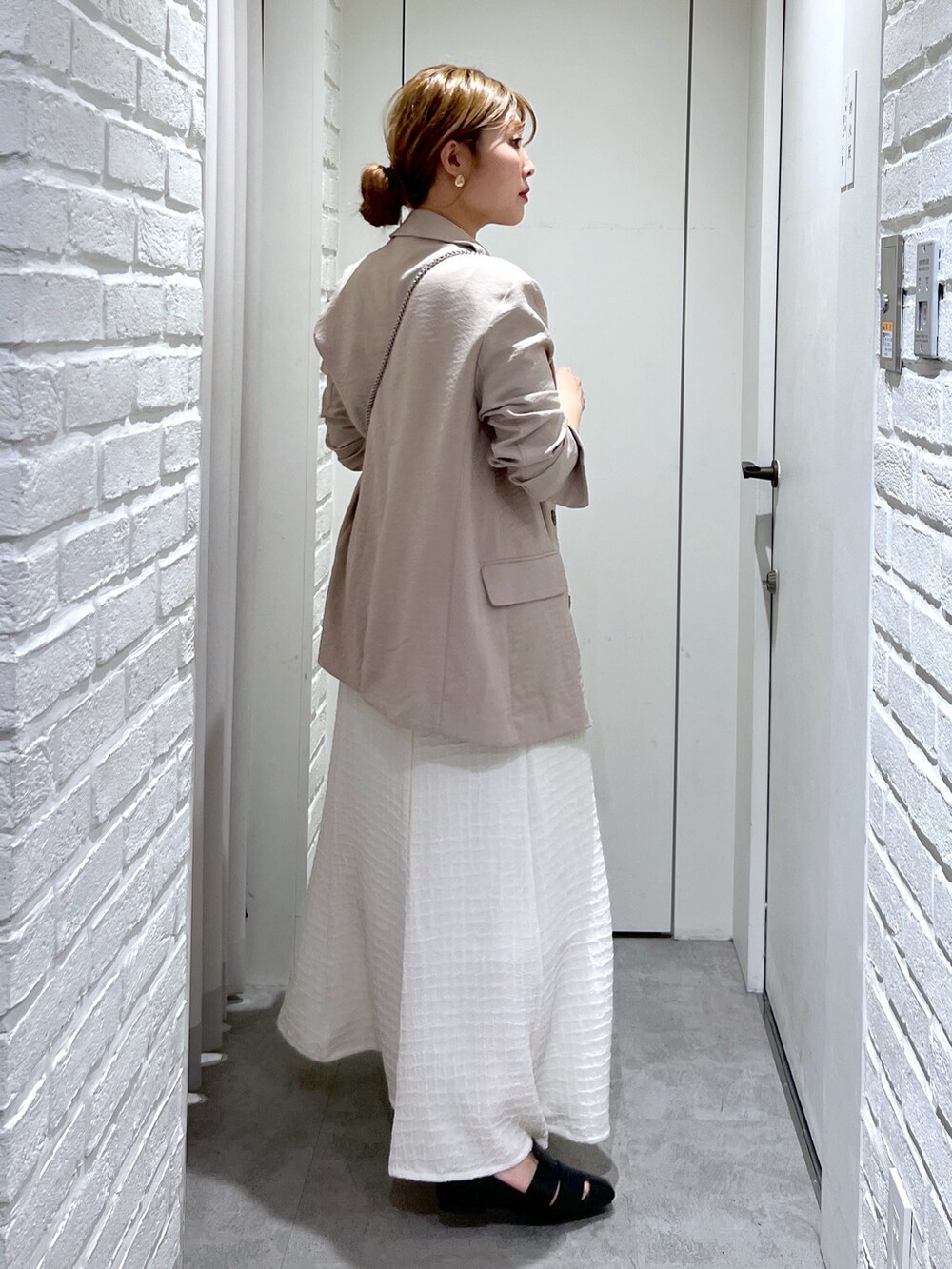 ホワイト系のワンピース、ゴールド系のショルダーバッグ、ブラック系のスリッポンを着用したレディースの春コーディネートの4枚目の写真