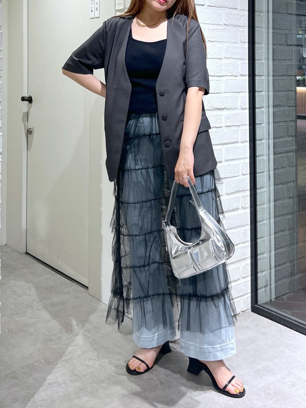 グレー系のノーカラージャケット、ブラック系のスカート、ブルー系のデニムパンツを着用したレディースの夏コーディネートの5枚目の写真