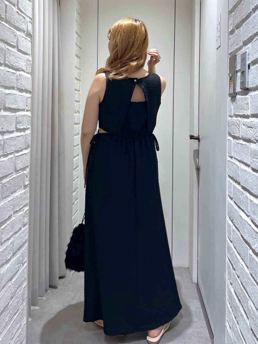 ブラック系のワンピース、ブラック系のハンドバッグ、ホワイト系のサンダルを着用したレディースの夏コーディネートの8枚目の写真