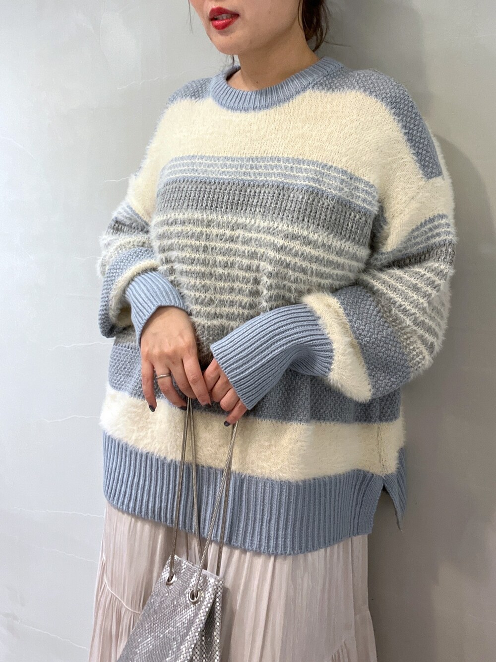 ブルー系のニット/セーター、ホワイト系のスカート、シルバー系のショルダーバッグを着用したレディースの冬コーディネートの7枚目の写真