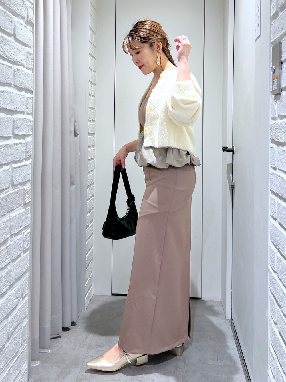 ブラウン系のワンピース、ブラック系のショルダーバッグ、ゴールド系のパンプスを着用したレディースの冬コーディネートの3枚目の写真