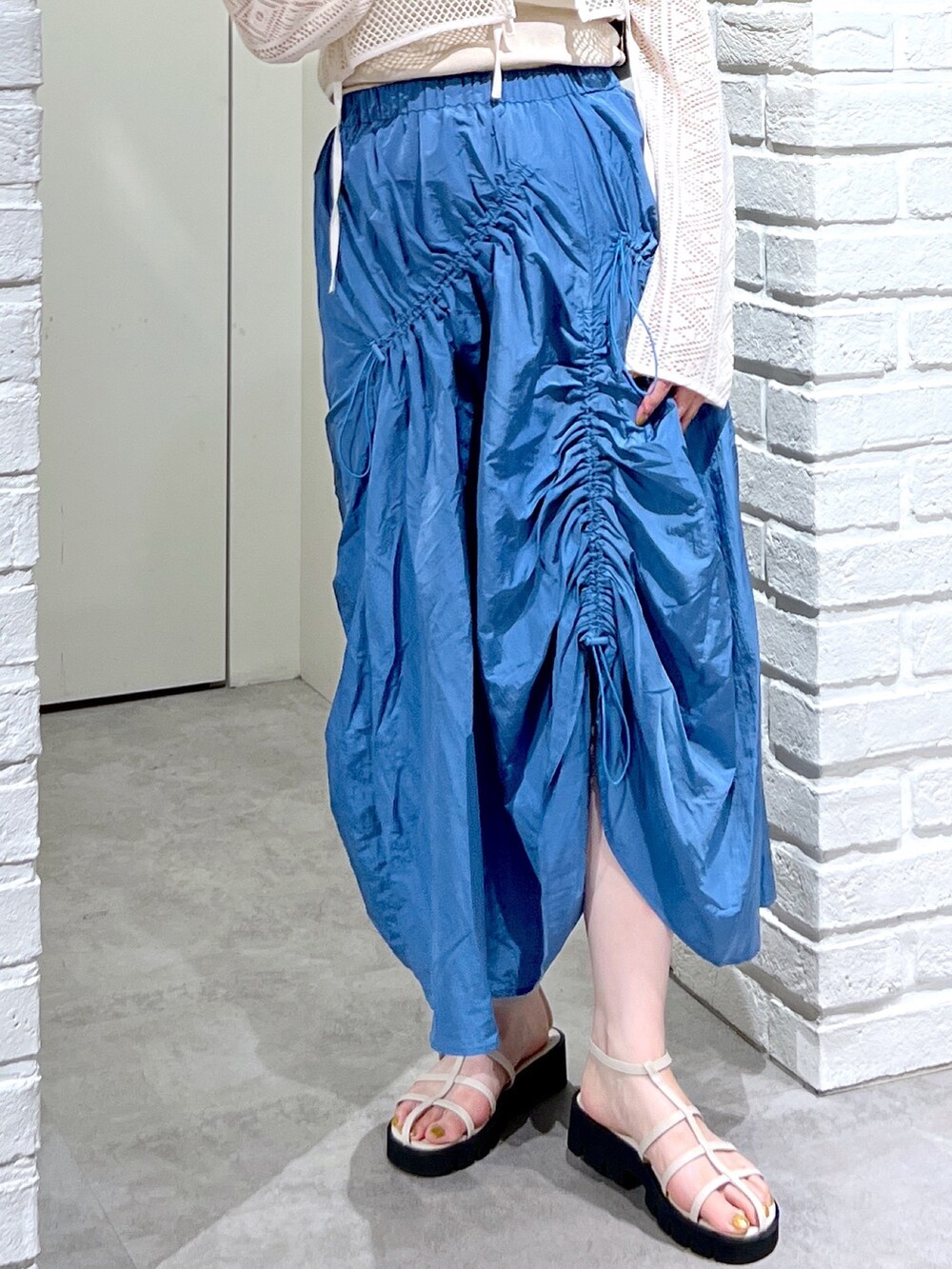 ブルー系のスカート、ホワイト系のカーディガン/ボレロ、ホワイト系のサンダルを着用したレディースの夏コーディネートの7枚目の写真