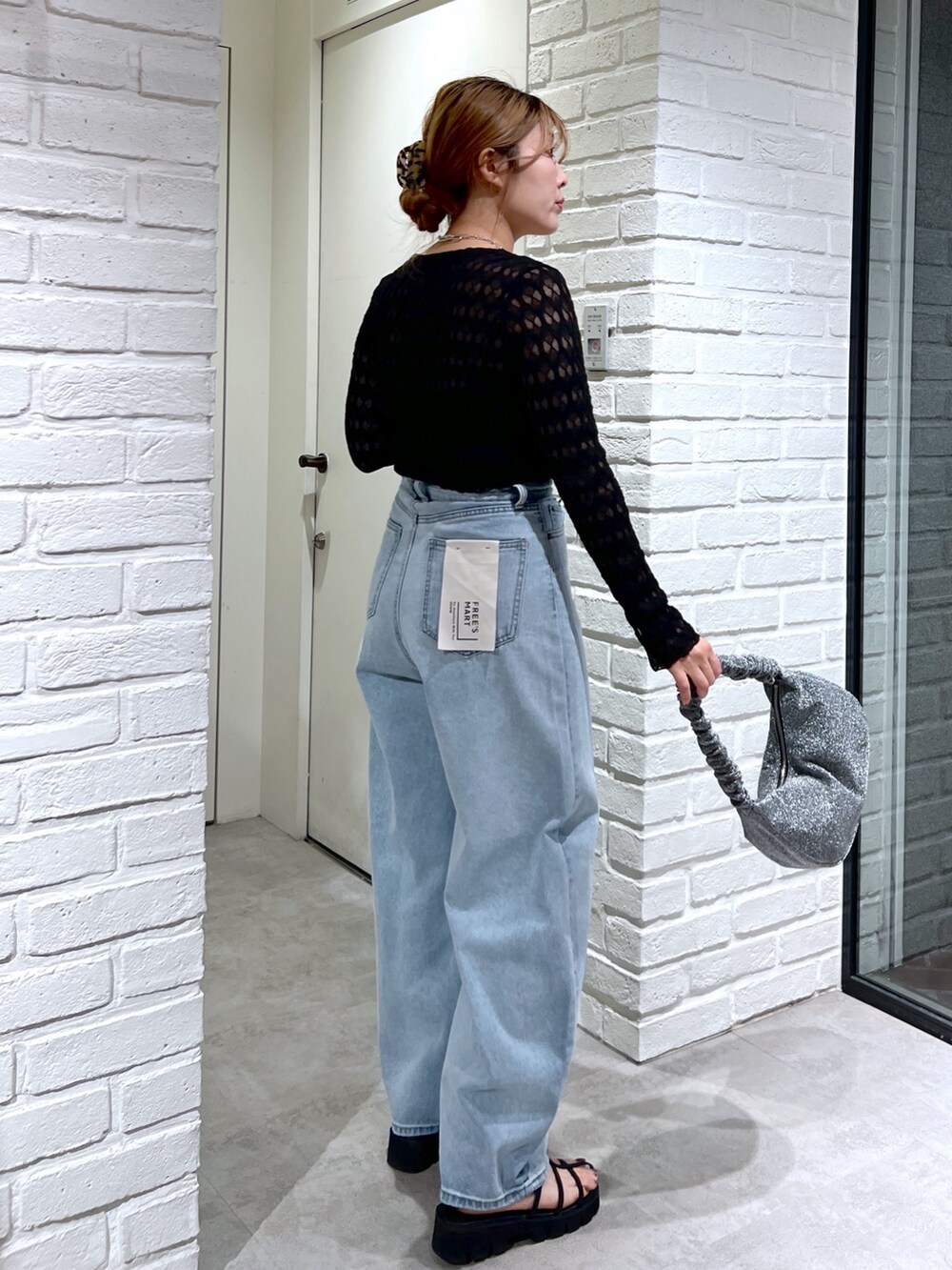 ブルー系のデニムパンツ、ブラック系のサンダル、シルバー系のハンドバッグを着用したレディースの夏コーディネートの3枚目の写真