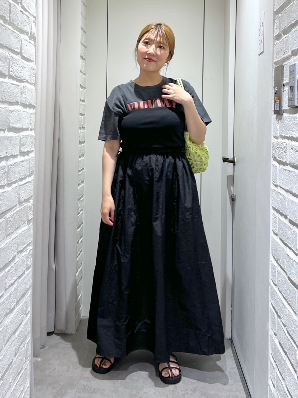 ブラック系のワンピース、ブラック系のTシャツ/カットソー、グリーン系のかごバッグを着用したレディースの夏コーディネートの2枚目の写真