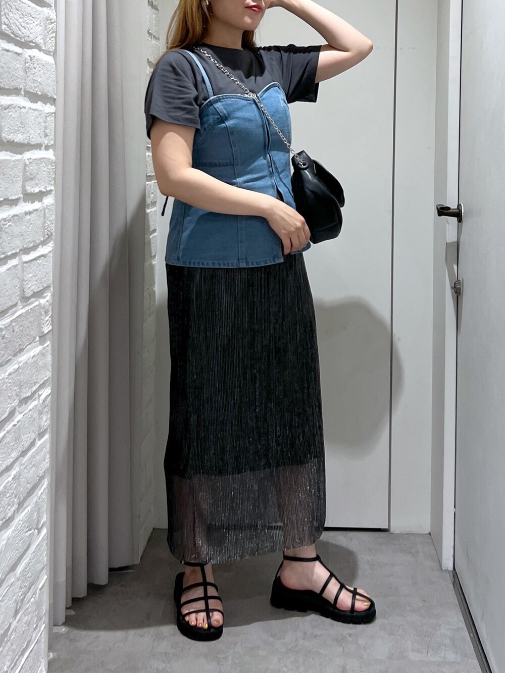 ブラック系のスカート、ブルー系のベスト、ブラック系のショルダーバッグを着用したレディースの夏コーディネートの6枚目の写真