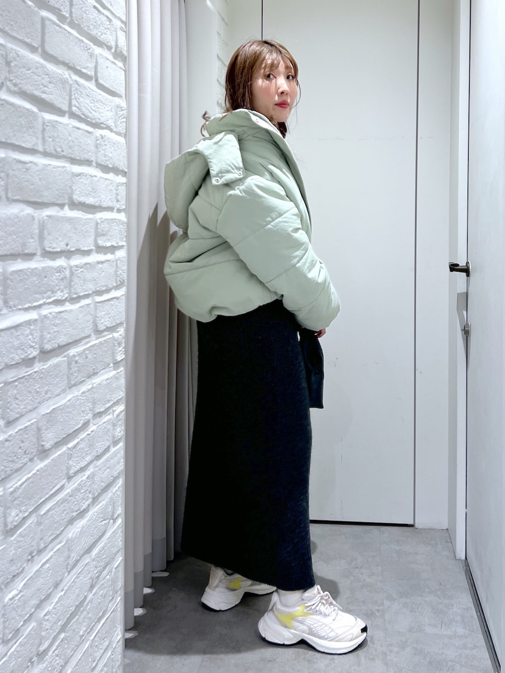 ブラック系のワンピース、グリーン系のブルゾン、ブラック系のショルダーバッグを着用したレディースの冬コーディネートの2枚目の写真