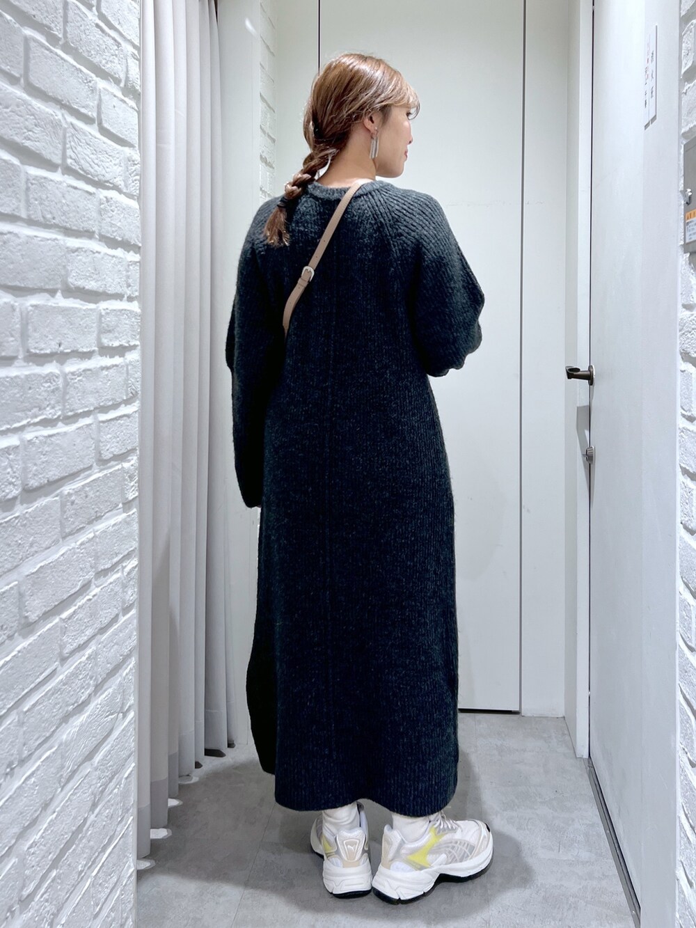 ブラック系のワンピース、ホワイト系のスニーカー、ベージュ系のショルダーバッグを着用したレディースの冬コーディネートの5枚目の写真