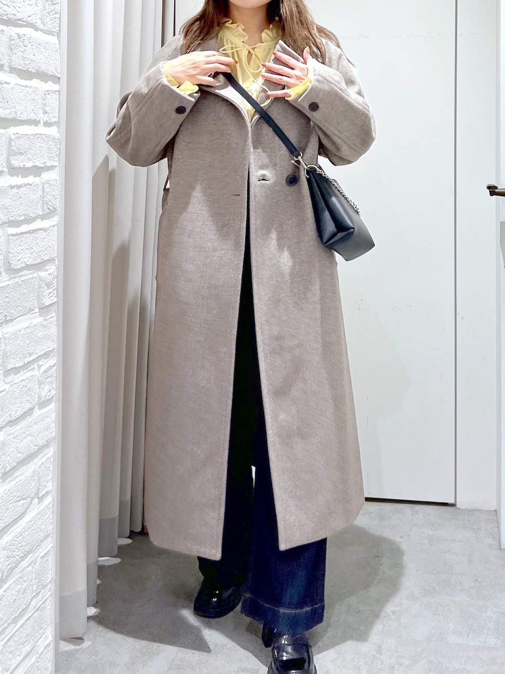 ブラウン系のステンカラーコート、ブラック系のショルダーバッグ、イエロー系のシャツ/ブラウスを着用したレディースの秋コーディネートの5枚目の写真