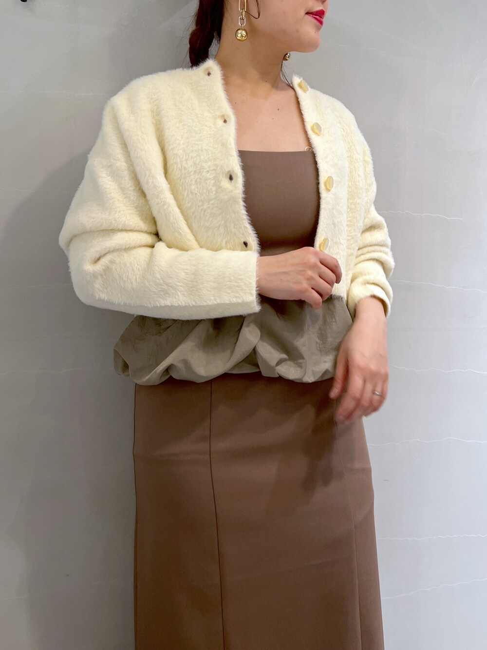 ブラウン系のワンピース、ブラック系のショルダーバッグ、ゴールド系のパンプスを着用したレディースの冬コーディネートの6枚目の写真