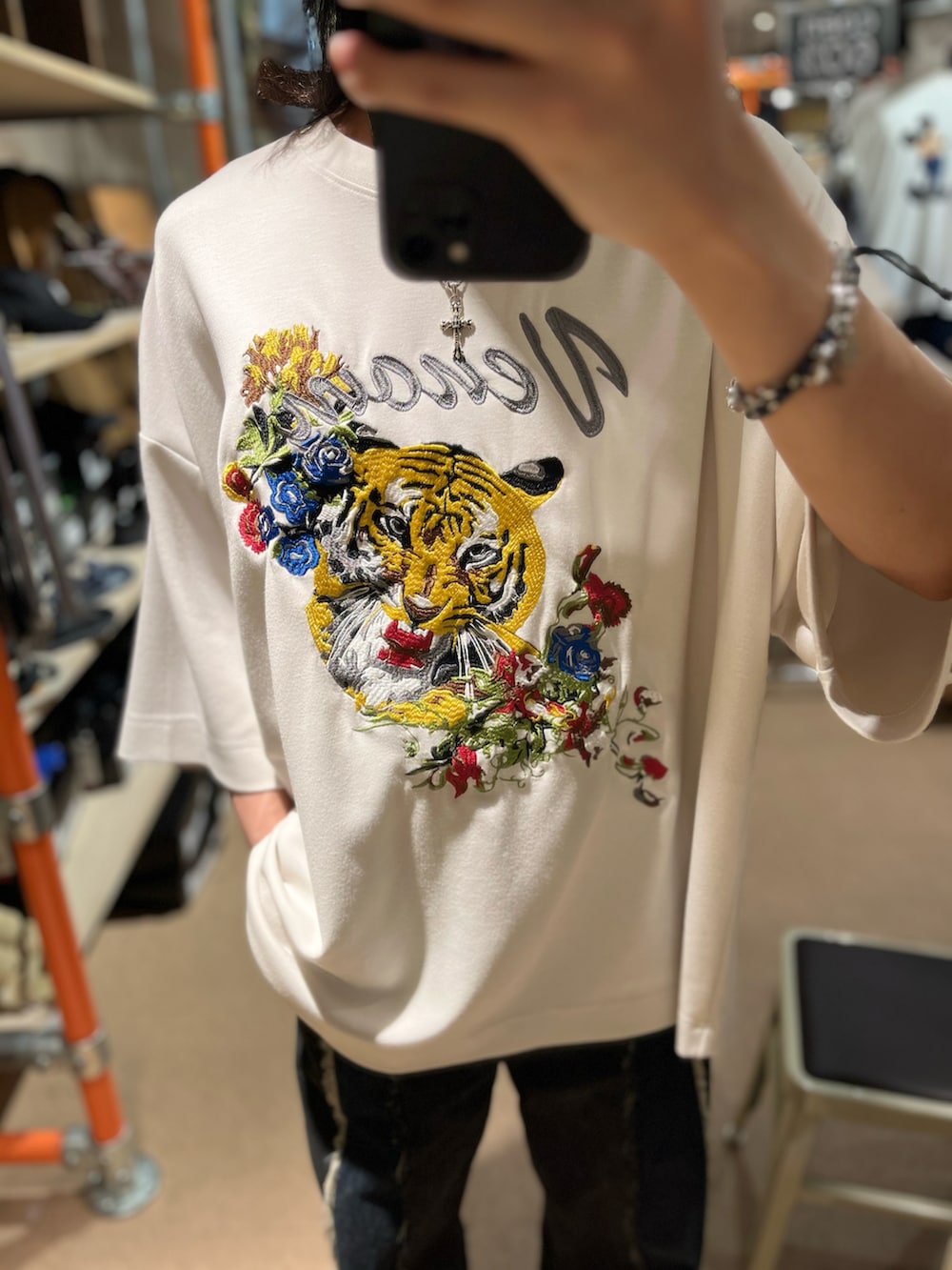 ブラック系のデニムパンツ、ホワイト系のTシャツ/カットソー、シルバー系のチャームを着用したメンズの春コーディネートの2枚目の写真