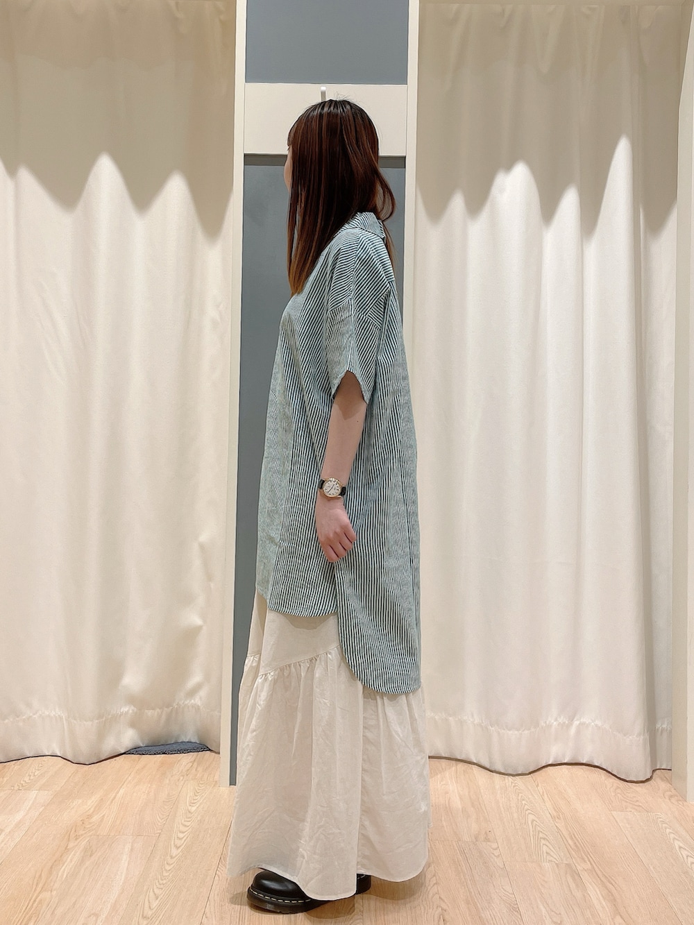 グリーン系のチュニック、ホワイト系のスカートを着用したレディースの夏コーディネートの2枚目の写真