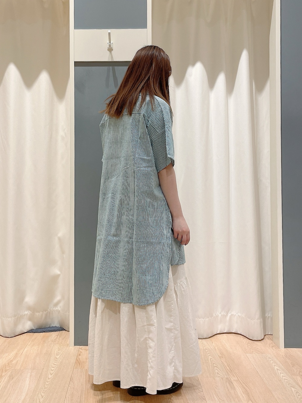 グリーン系のチュニック、ホワイト系のスカートを着用したレディースの夏コーディネートの3枚目の写真