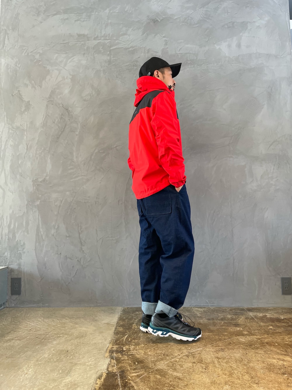 ブルー系のデニムパンツ、レッド系のマウンテンパーカーを着用したメンズの春コーディネートの2枚目の写真