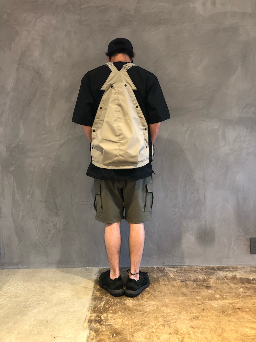 グリーン系のカーゴパンツ、ベージュ系のベスト、ブラック系のTシャツ/カットソーを着用したメンズの春コーディネートの2枚目の写真