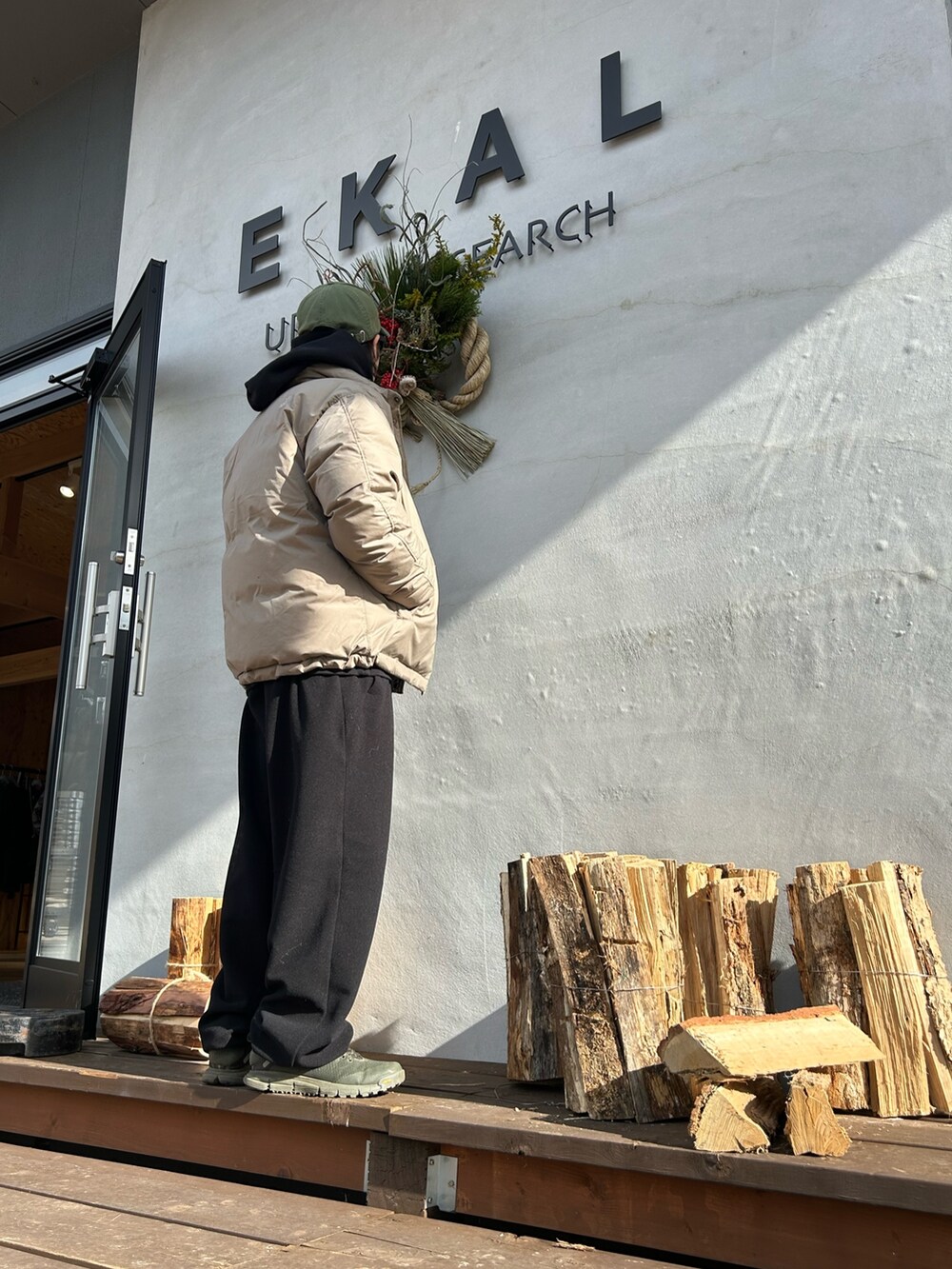 ブラック系のパーカー、ベージュ系のその他アウター、ブラック系のメガネを着用したメンズの冬コーディネートの2枚目の写真