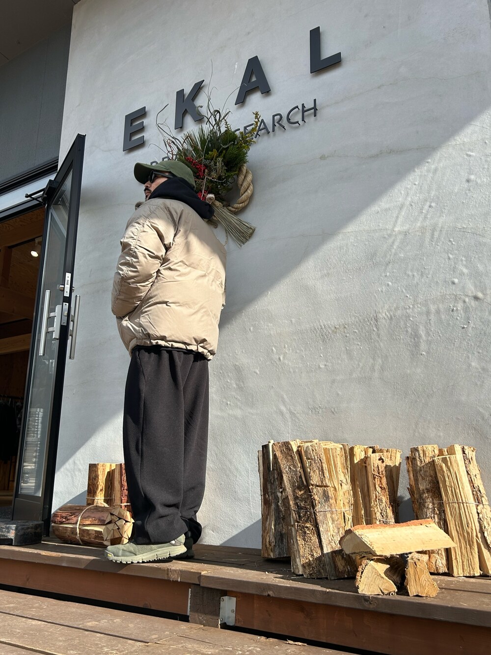 ブラック系のパーカー、ベージュ系のその他アウター、ブラック系のメガネを着用したメンズの冬コーディネートの3枚目の写真