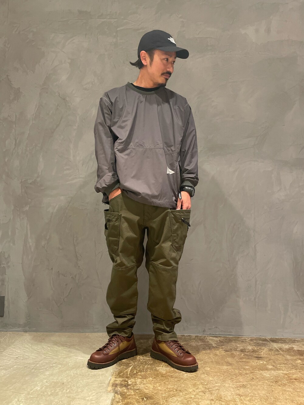 グリーン系のカーゴパンツ、グレー系のトップス、ブラウン系のブーツを着用したメンズの春コーディネートの4枚目の写真