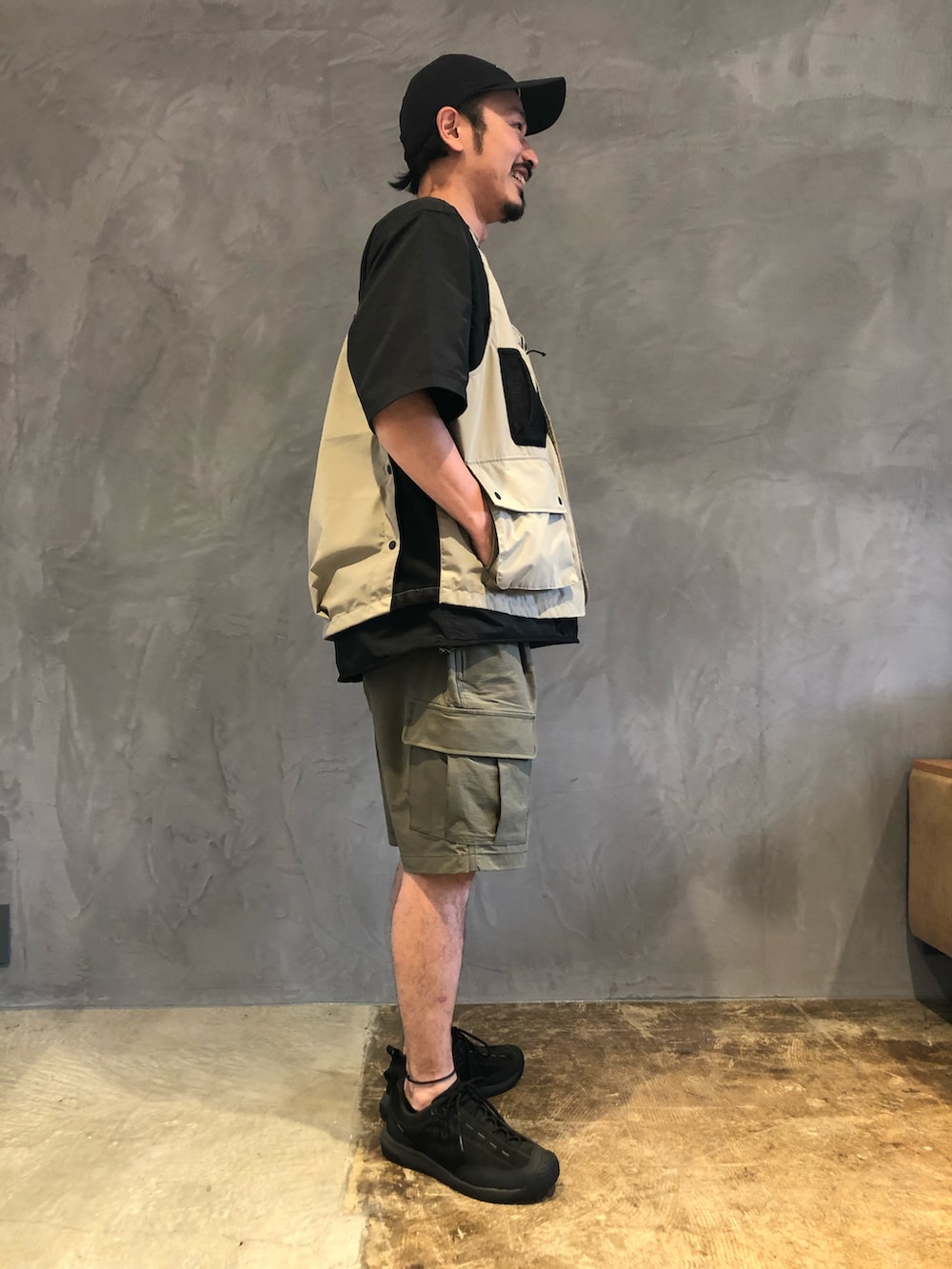 グリーン系のカーゴパンツ、ベージュ系のベスト、ブラック系のTシャツ/カットソーを着用したメンズの春コーディネートの4枚目の写真