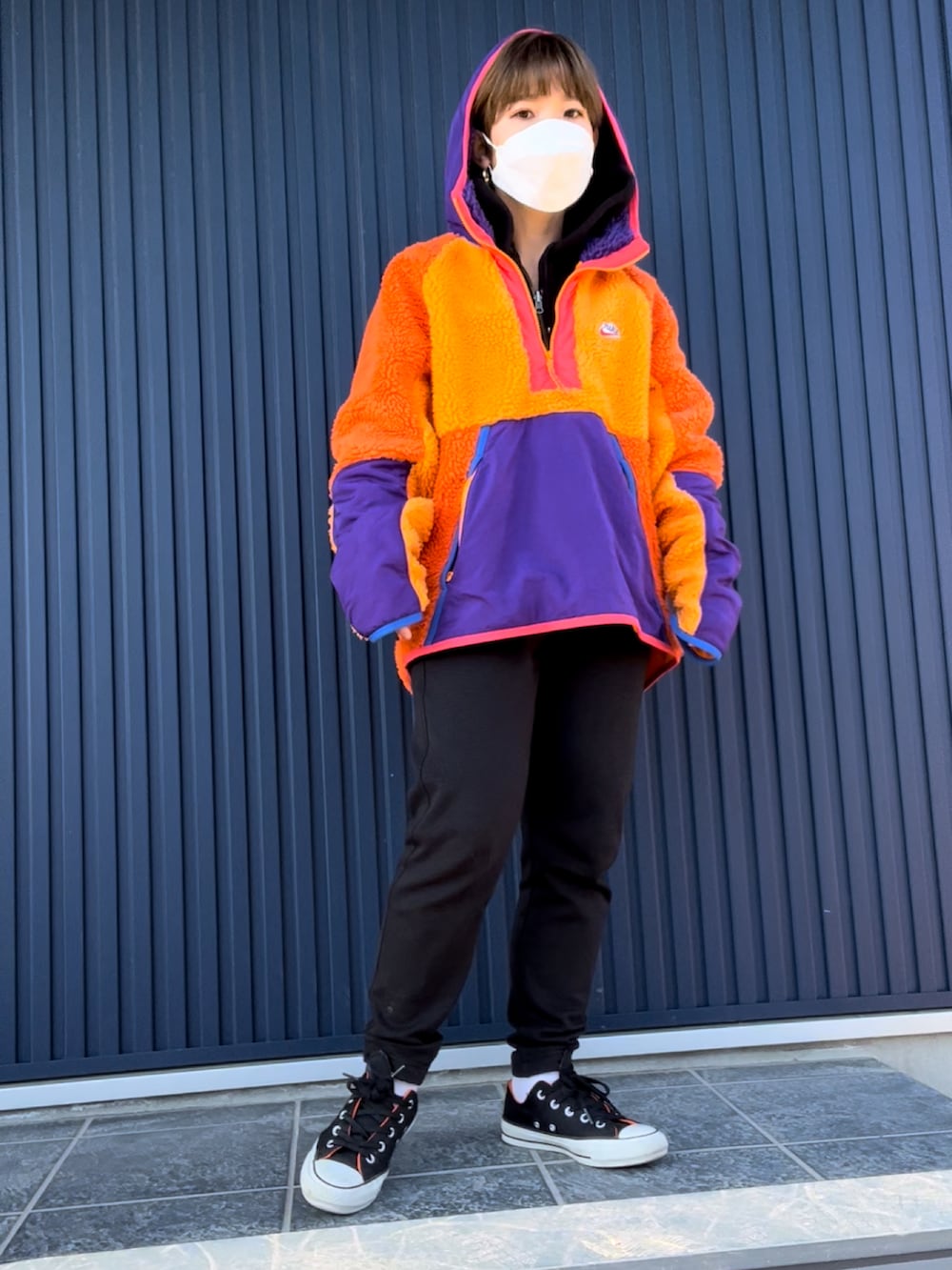 オレンジ系のその他アウター、ブラック系のスニーカー、ブラック系のスウェットパンツを着用したレディースの冬コーディネートの2枚目の写真