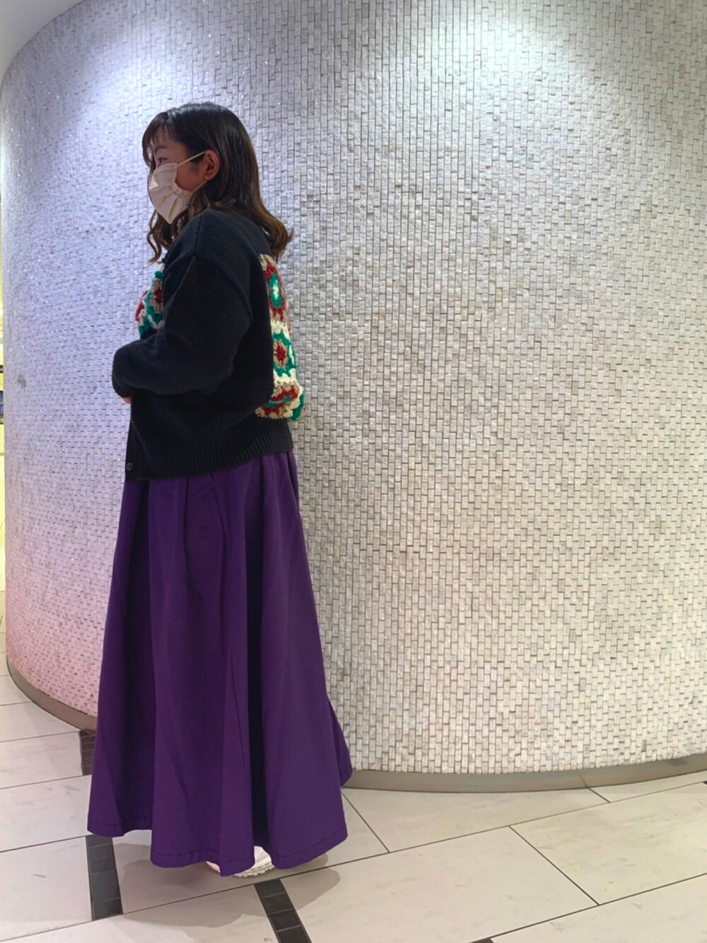 ブラック系のニット/セーター、パープル系のスカート、ホワイト系のスニーカーを着用したレディースの春コーディネートの2枚目の写真