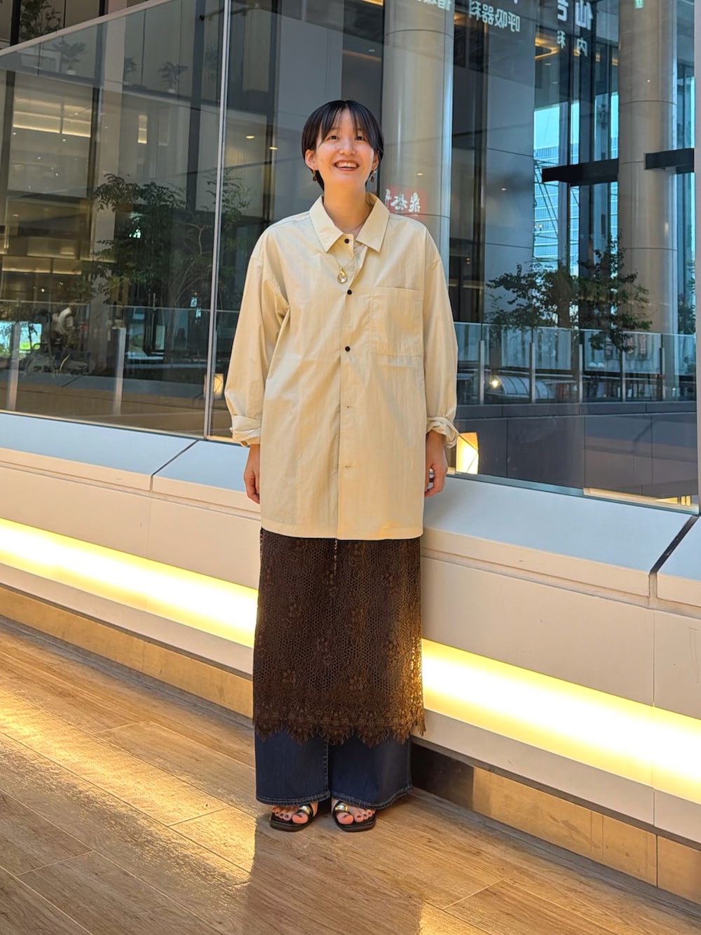 ブラック系のサンダル、ブルー系のデニムパンツ、ブラウン系のスカートを着用したレディースの夏コーディネートの2枚目の写真