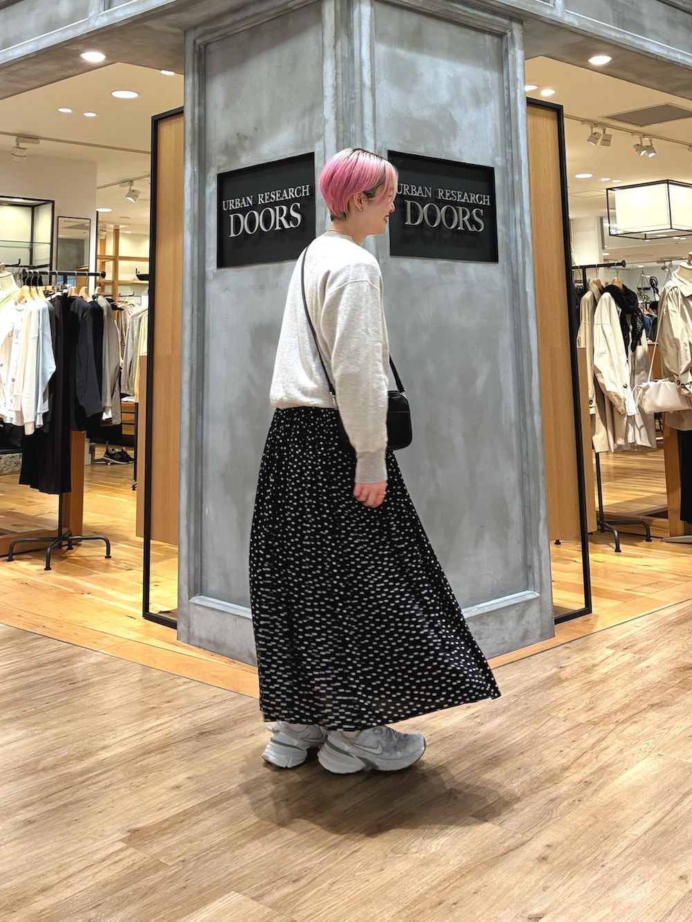 シルバー系のスニーカー、ベージュ系のスウェット、ブラック系のスカートを着用したレディースの春コーディネートの4枚目の写真