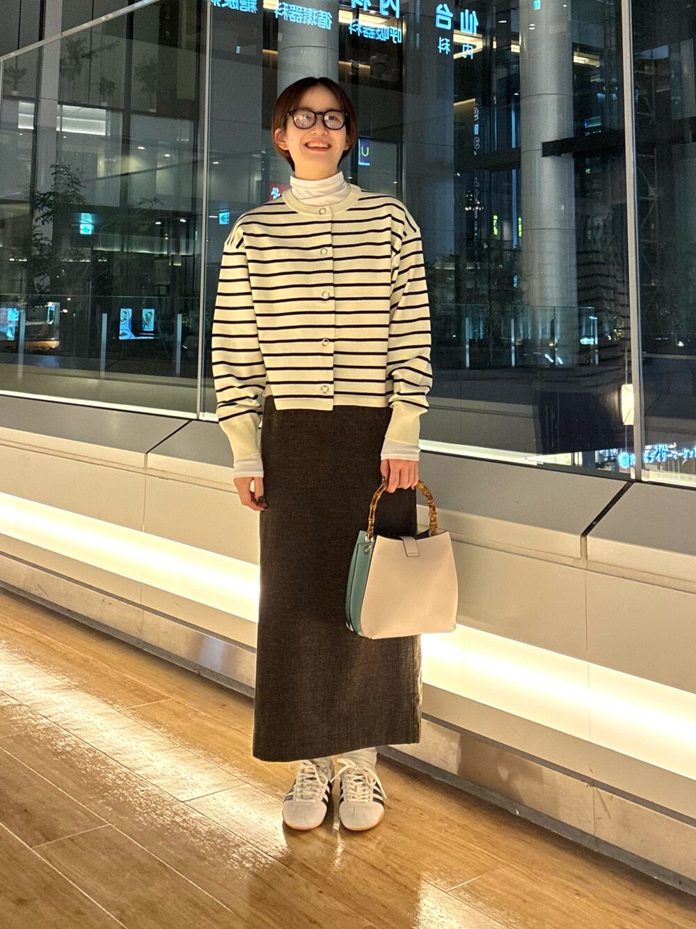 ホワイト系のカーディガン/ボレロ、グリーン系のTシャツ/カットソー、ブラウン系のスカートを着用したレディースの秋コーディネートの3枚目の写真